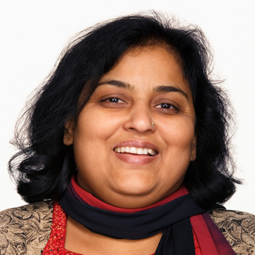 Smiling South Asian woman wearing scarf looks at camera
