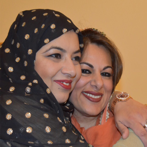 Closeup up of two women embracing, one wears a hijab