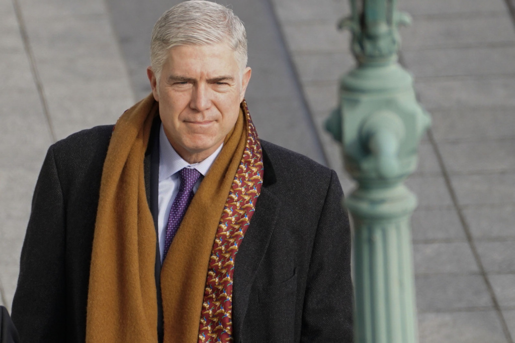 Photo of Justice Gorsuch walking outside wearing a scarf. 