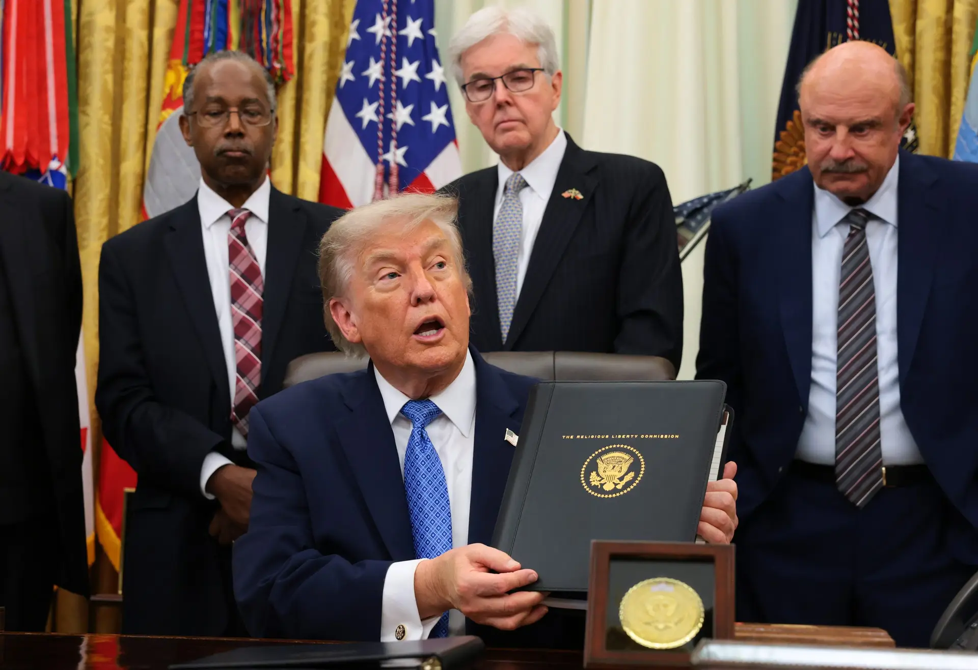 President Donald Trump displays the Religious Liberty Commission's draft report during an event in the Oval Office of the White House on June 26, 2026, in Washington, D.C. (Photo by Anna Moneymaker/Getty Images)